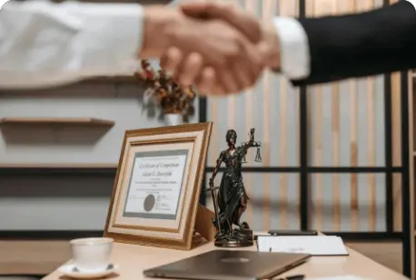 A man shaking hands with another person in front of a statue.